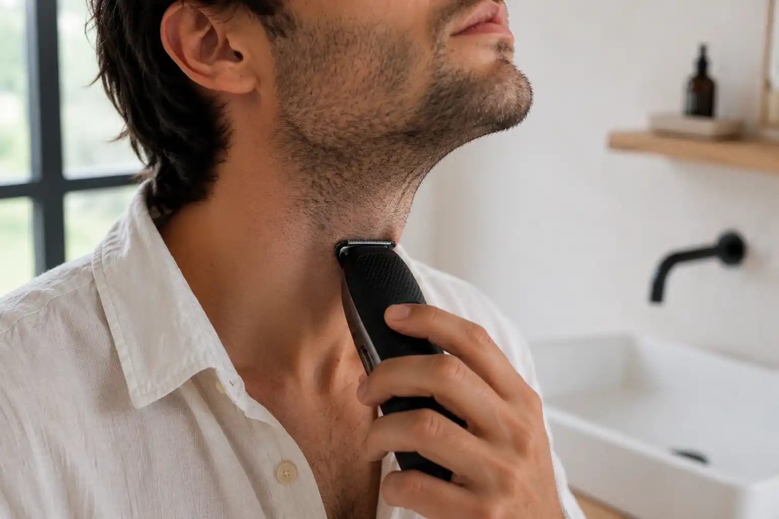 Close-up of a man trimming the neckline of his three-day stubble.